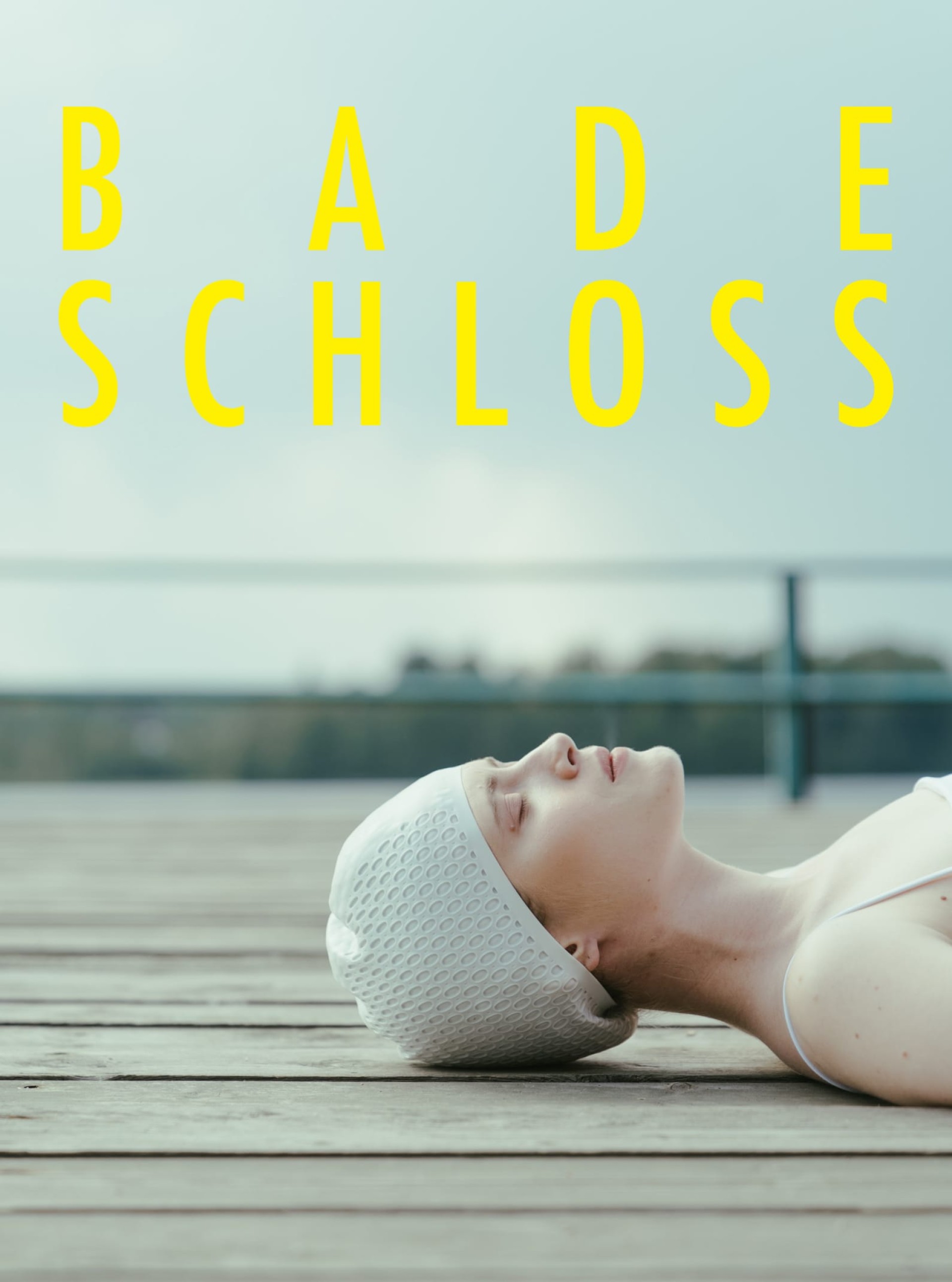 Eine Frau mit Badekappe liegt auf einem Steg. "BADESCHLOSS" steht in gelber Schrift oben.