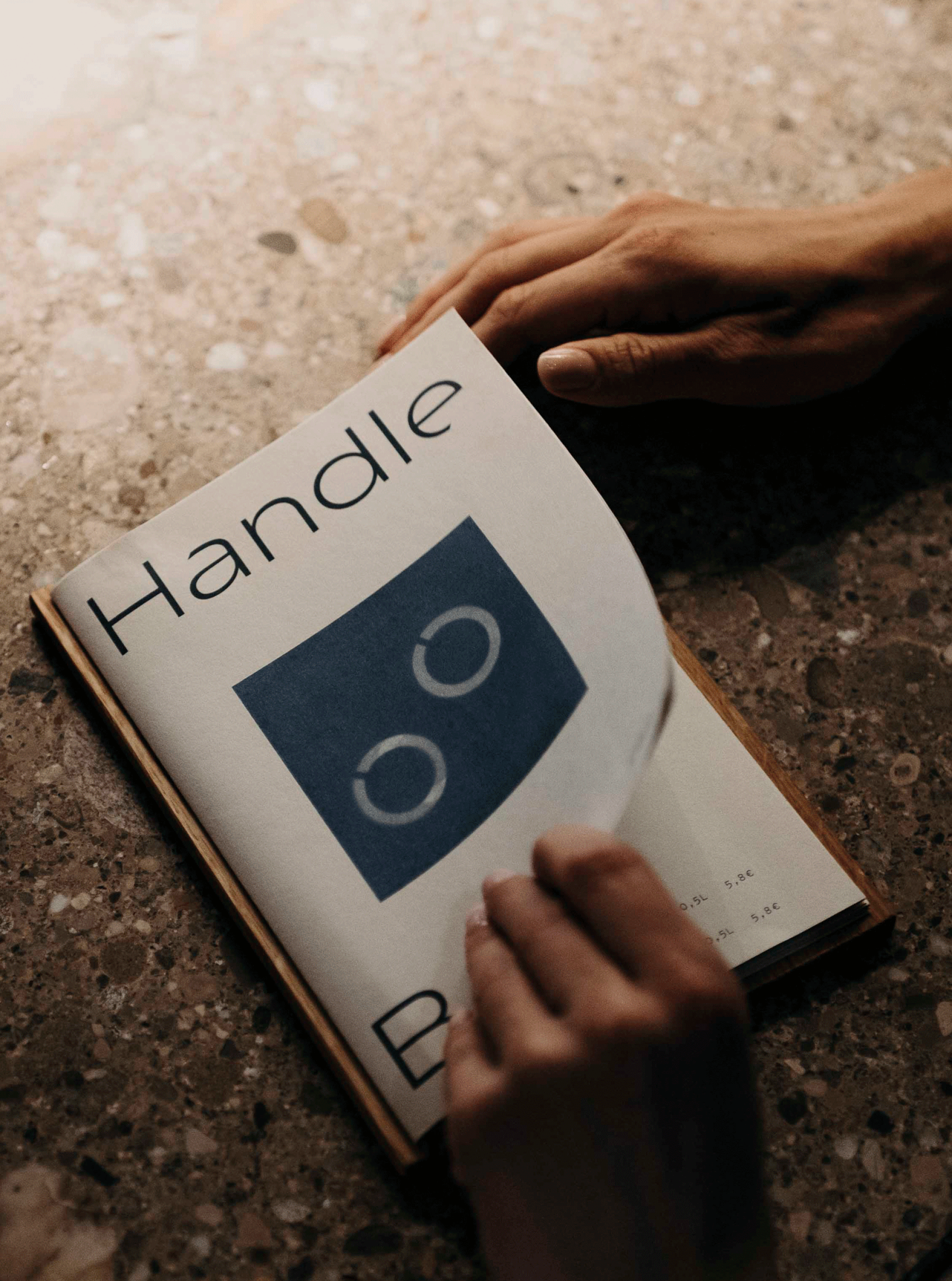 Nahaufnahme des "Handle Bar"-Menüs mit zwei Händen, die die Seite umblättern.