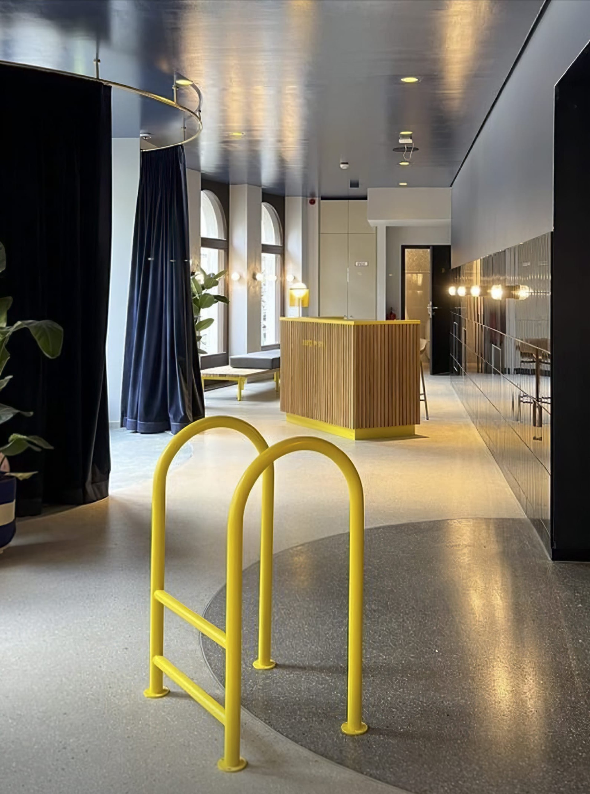 Gelber Fahrradständer vor Holztresen mit "Hotel Emmy"-Schild in einem modernen, stilvollen Innenraum.