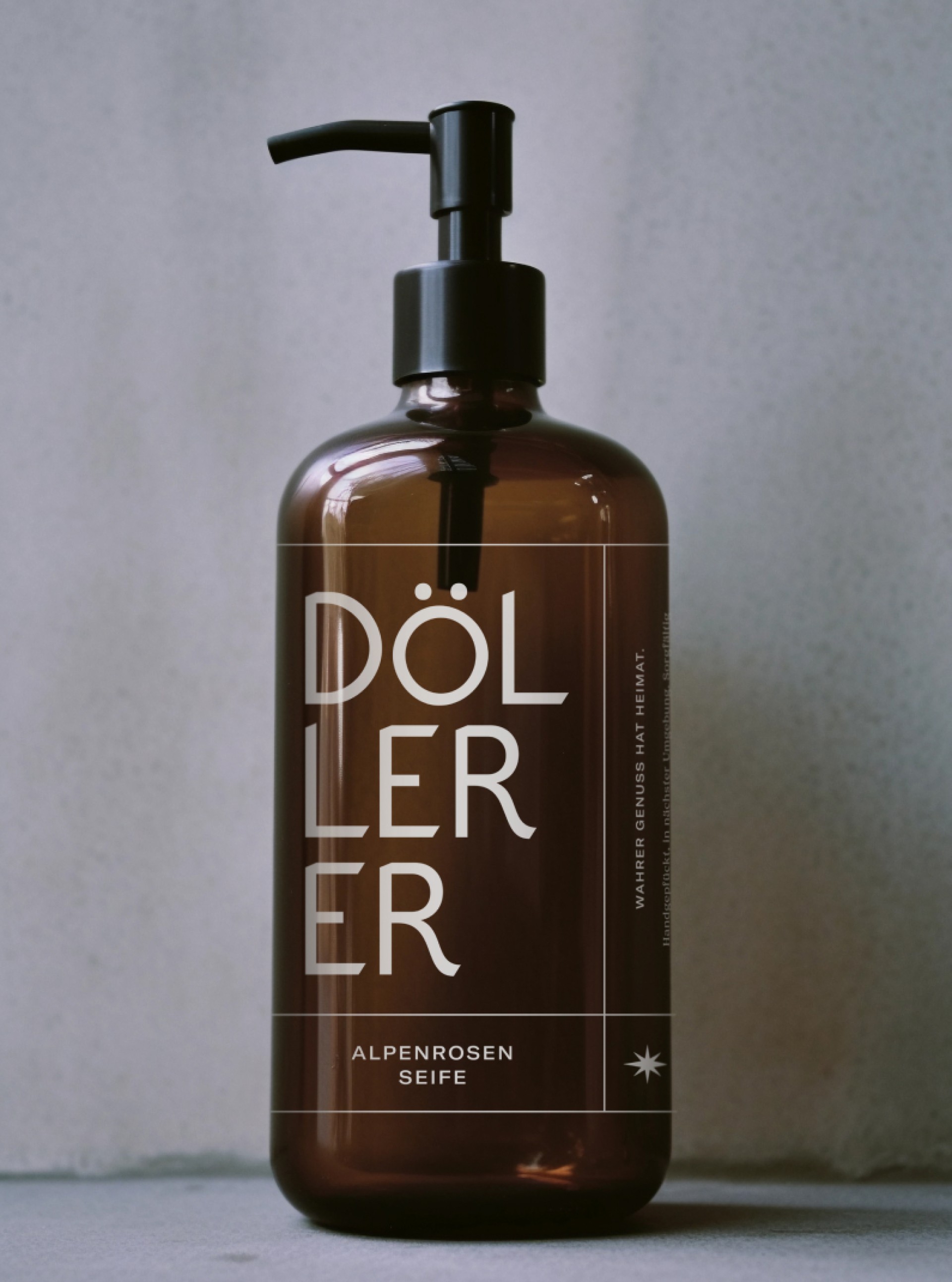 Braune DÖLLERER Seifenflasche mit schwarzer Pumpe. Aufschrift "DÖLLERER ALPENROSEN SEIFE. WAHRER GENUSS HAT HEIMAT".