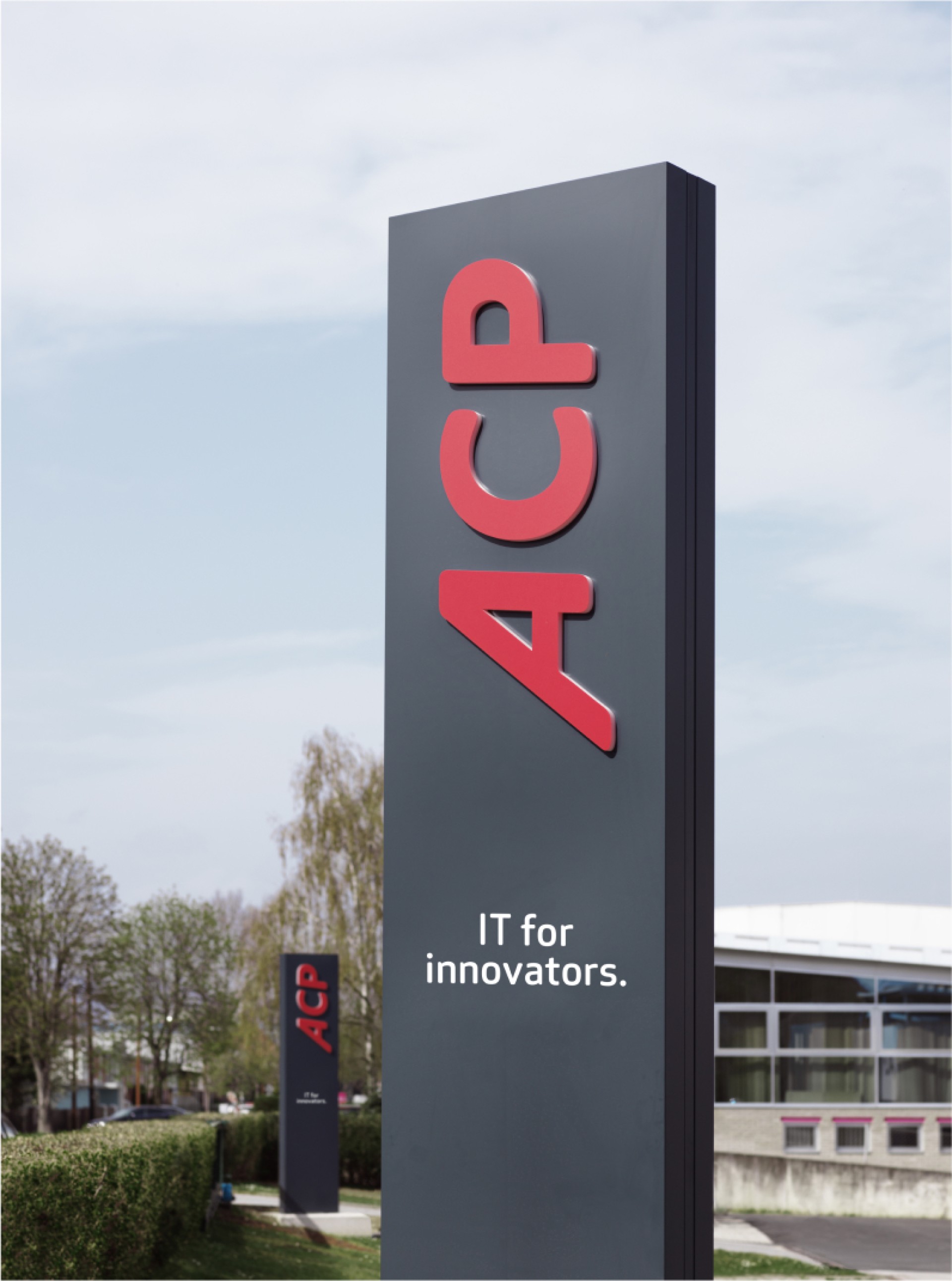 Dunkelgrauer ACP-Pfosten mit rotem Text "ACP IT for innovators.". Ein zweiter ACP-Pfosten ist im Hintergrund sichtbar.