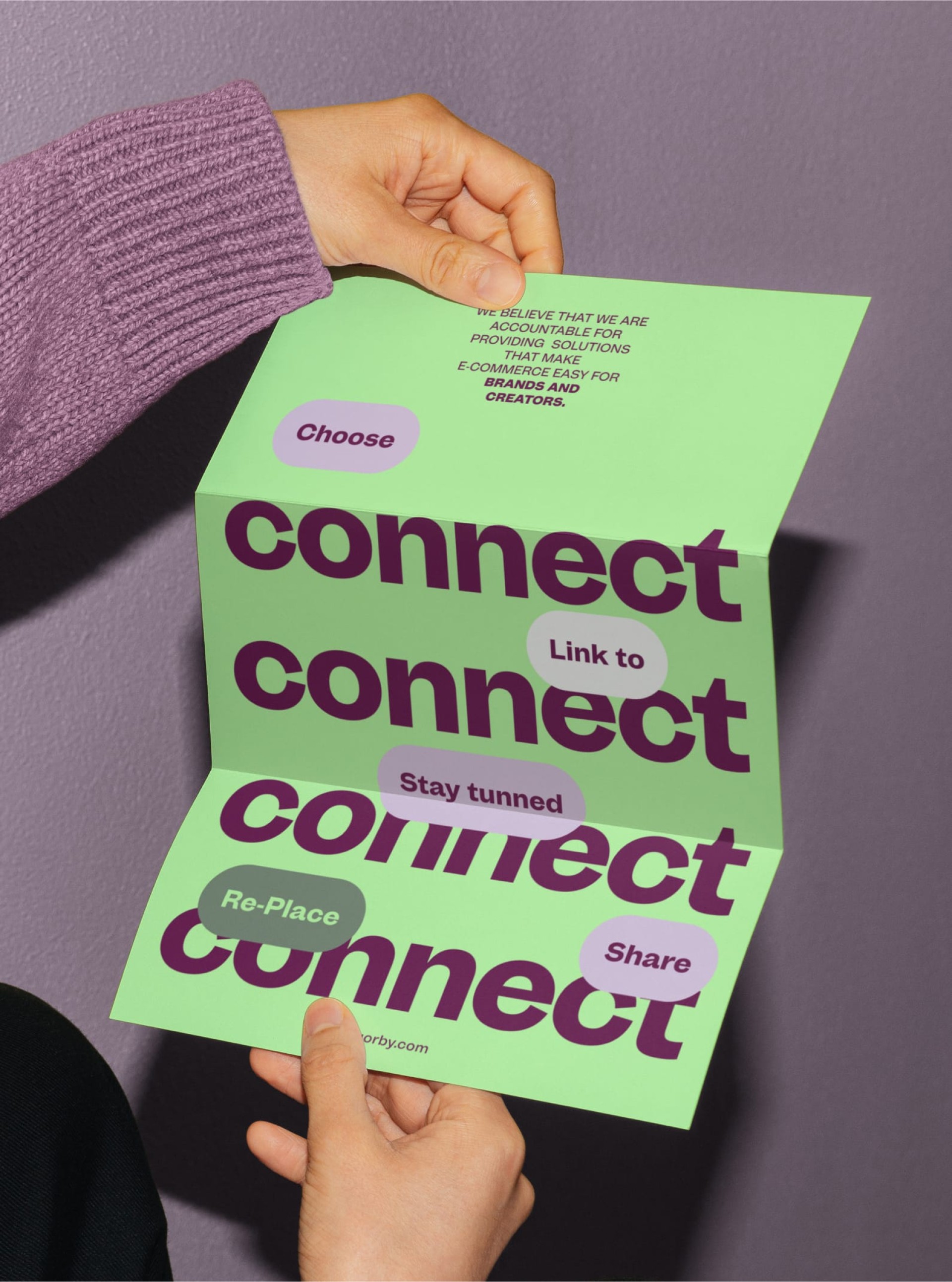 Eine gefaltete Broschüre "connect" in der Hand, mit Texten wie "Choose", "Link to", "Stay Tunned", "Re-Place" und "Share". orby.com steht unten.