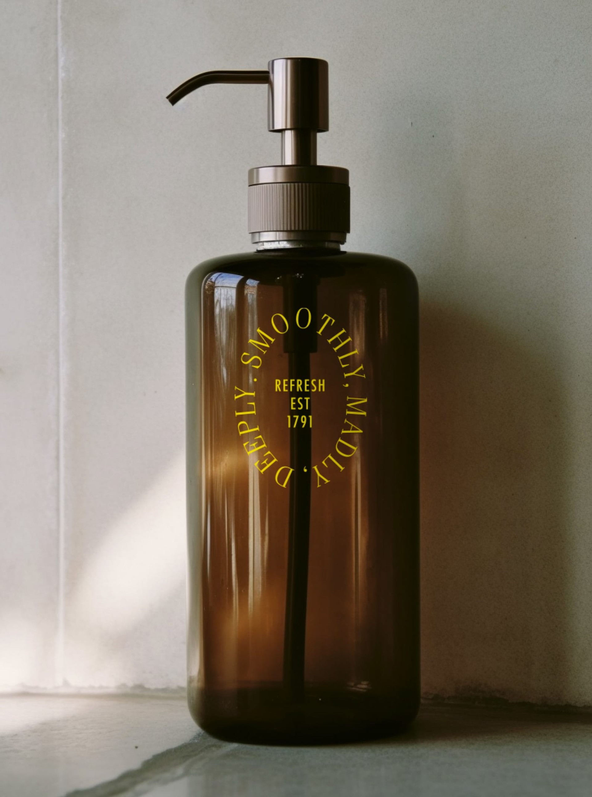 Eine bernsteinfarbene Seifenflasche mit gelbem Text: "DEEPLY SMOOTHLY MADLY. REFRESH EST 1791".