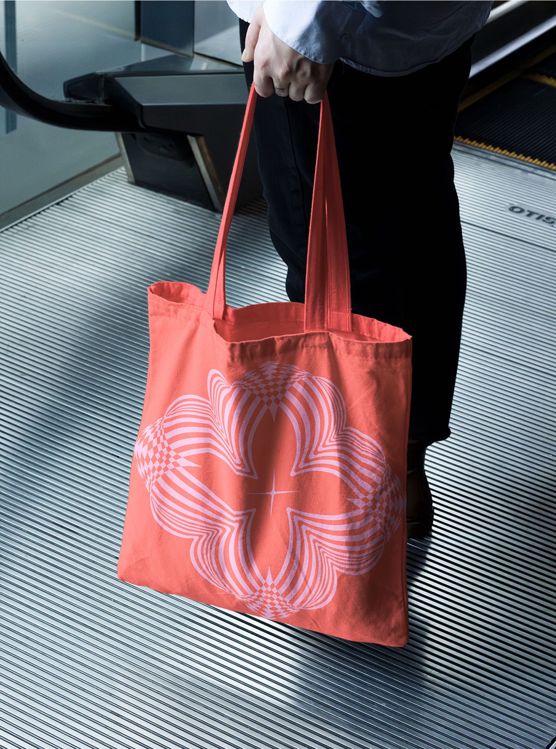 Eine Person hält eine korallenrote Tasche mit Blumenmuster auf einer Rolltreppe.