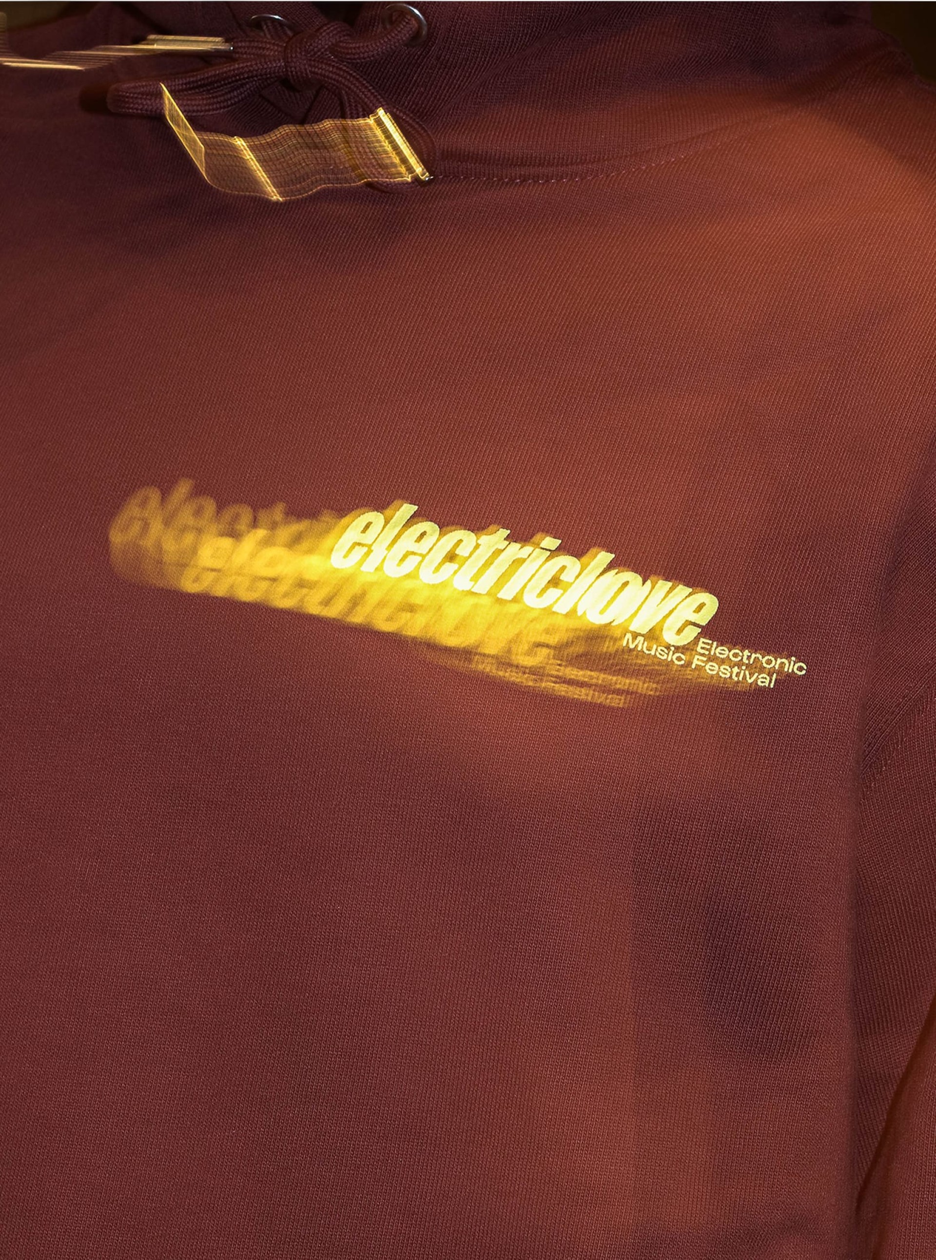 Nahaufnahme eines burgunderroten Electriclove Electronic Music Festival Hoodies mit Kordelzug.