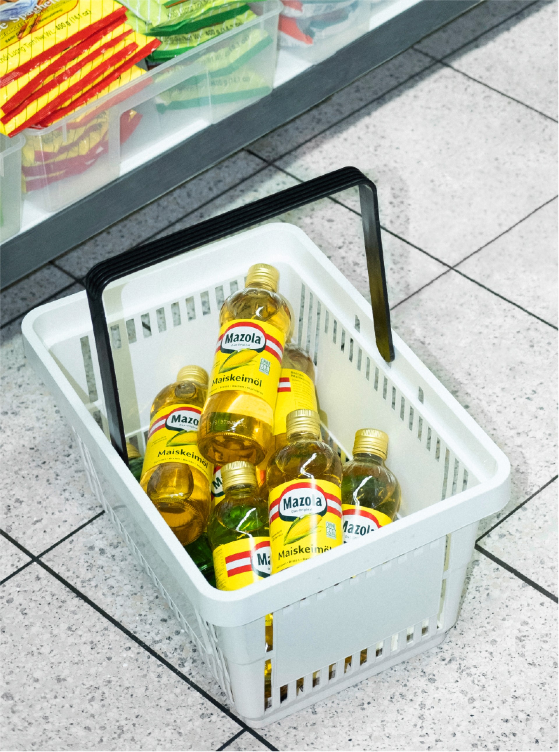 Einkaufskorb gefüllt mit Mazola Maiskeimölflaschen im Supermarkt.