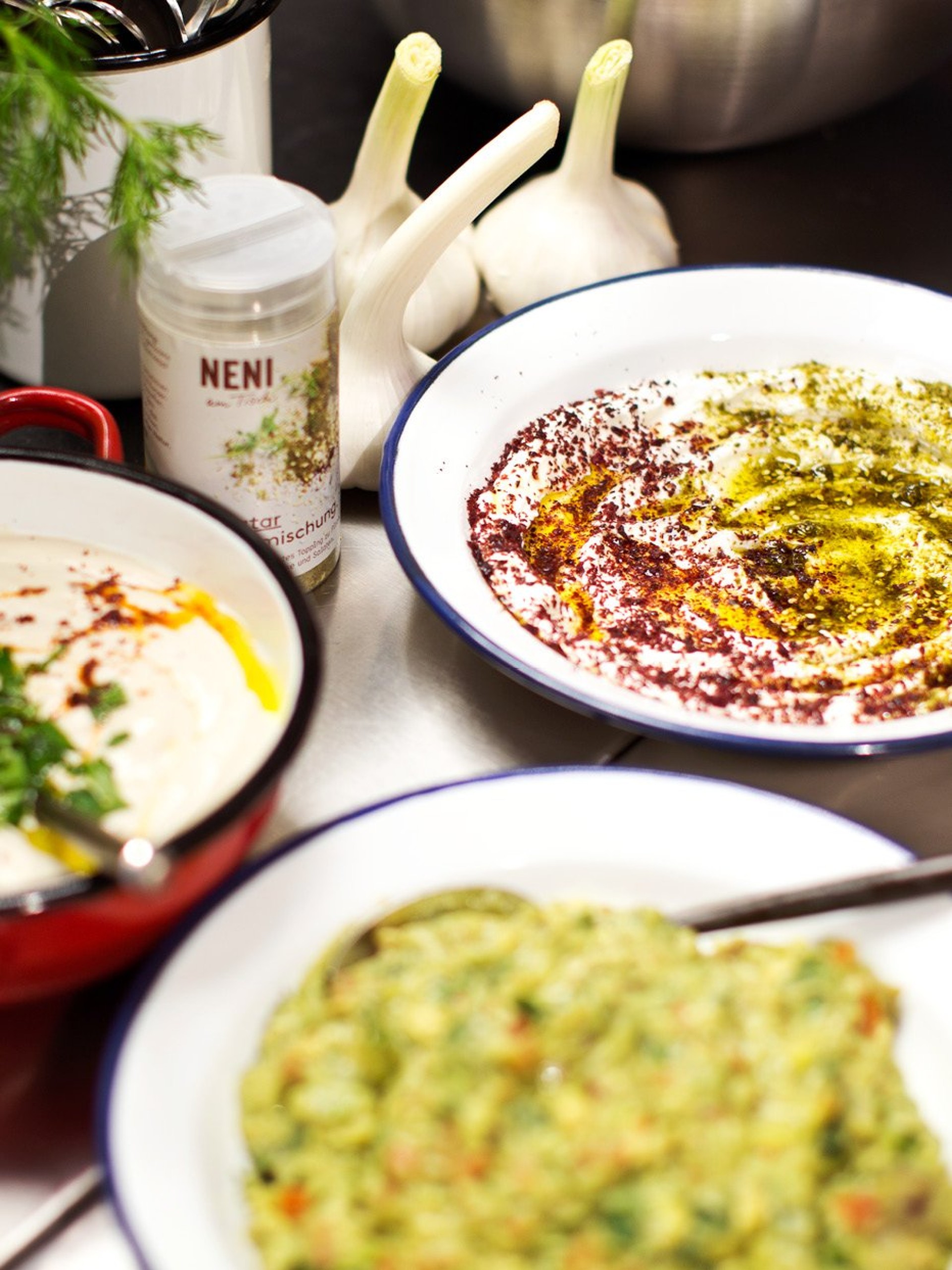 Nahaufnahme von Hummus, Neni-Gewürz und Knoblauch auf einer Theke.