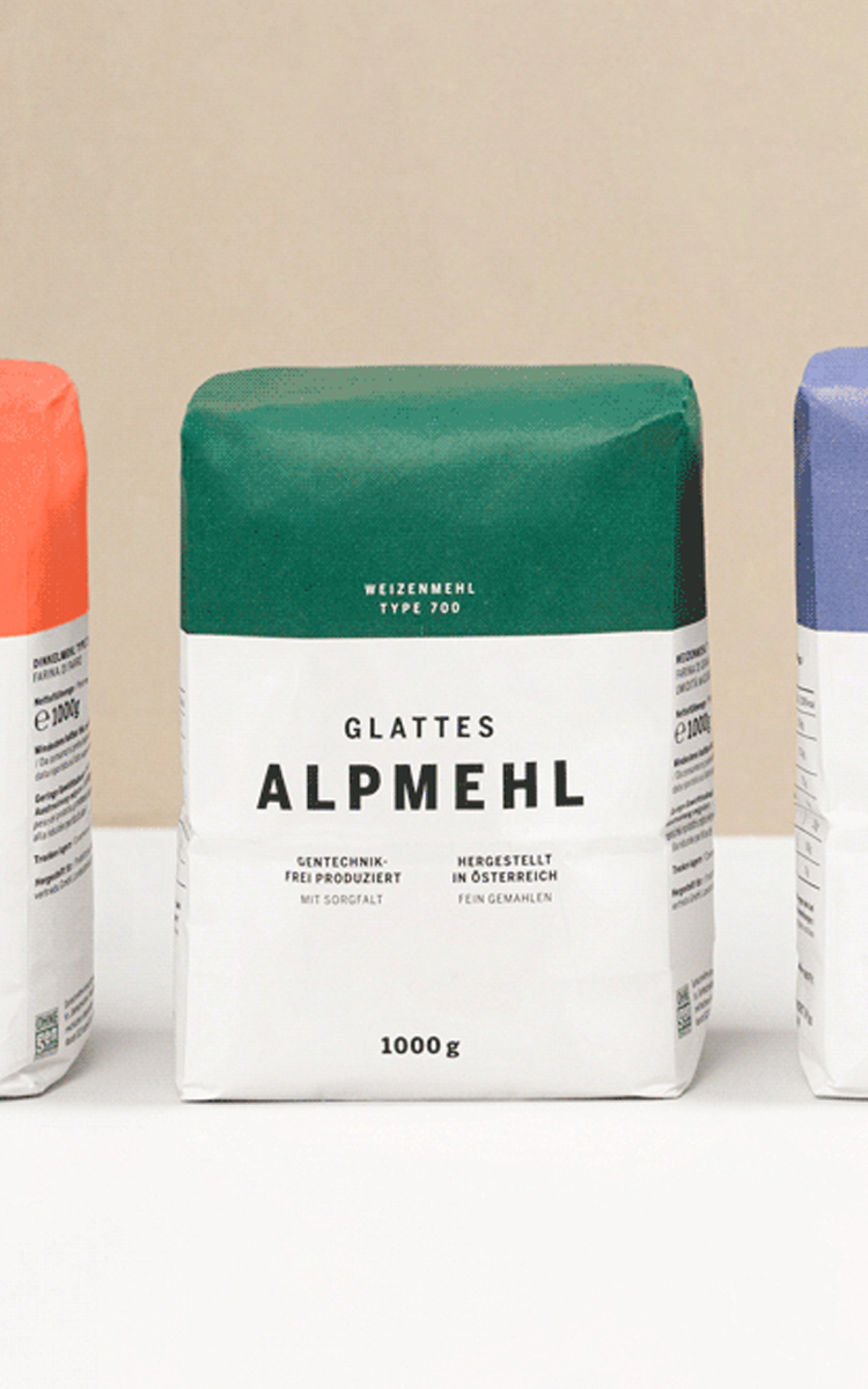 Drei Mehltüten: orange, grün (mit "Glattes Alpmehl" Text), lila.