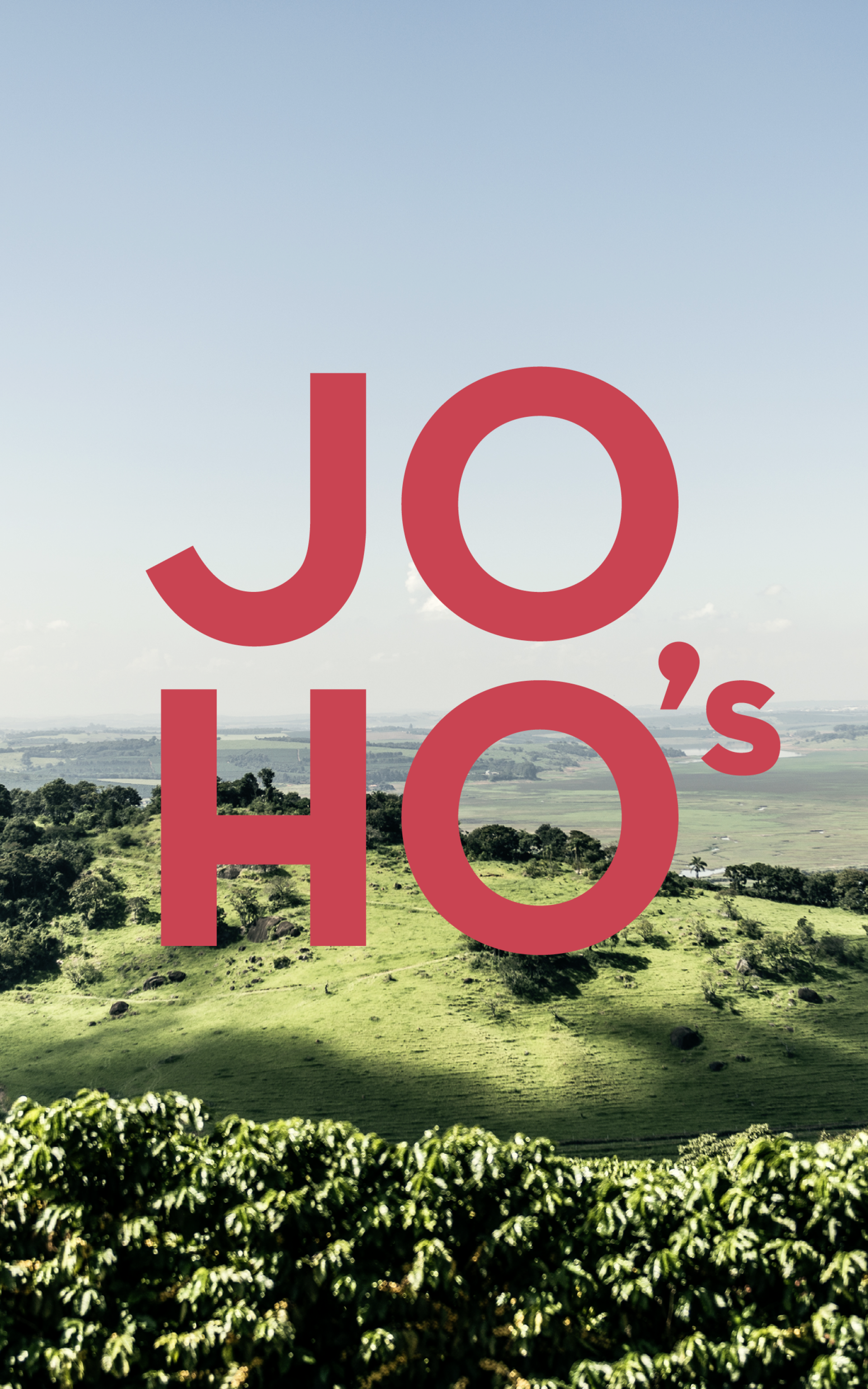 Ein ländliches Bild mit dem roten Text „JO HO's“ vor einem grünen Hügel mit Bäumen und blauem Himmel.