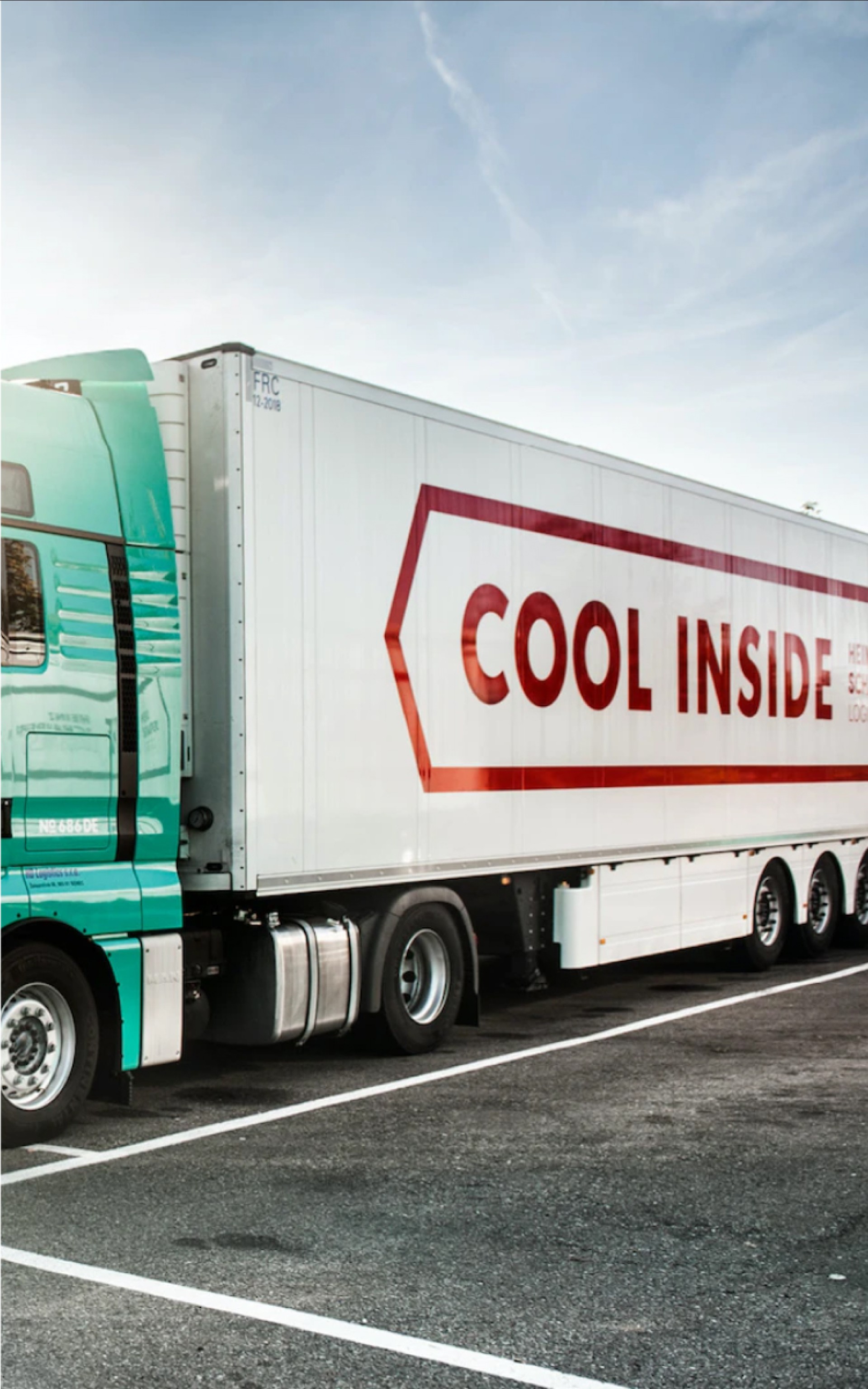 Ein grüner Sattelzug parkt, mit der roten Aufschrift "COOL INSIDE" auf dem weißen Anhänger.
