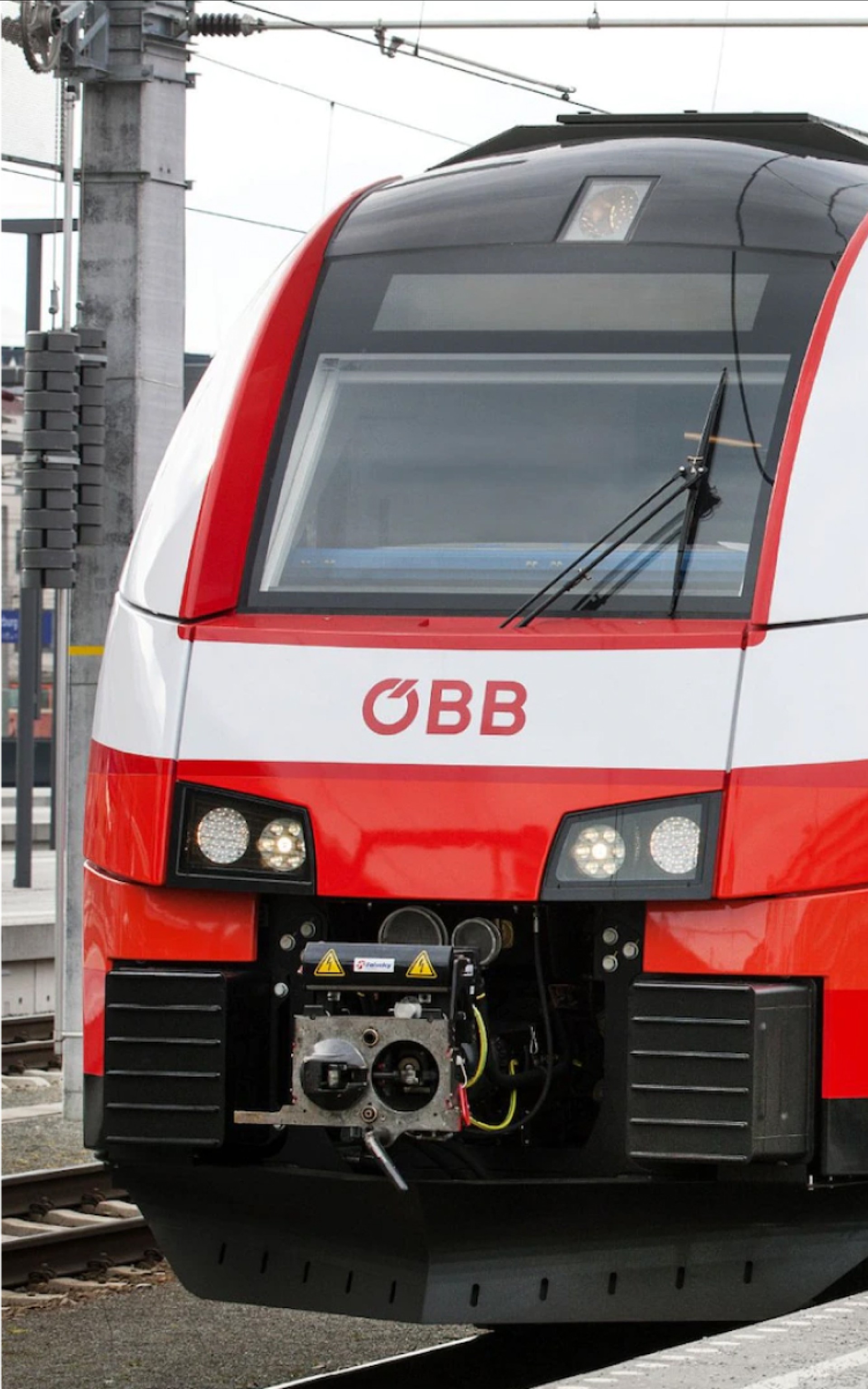 Nahaufnahme eines roten und weißen ÖBB-Zuges auf Gleisen. Das ÖBB-Logo ist sichtbar.