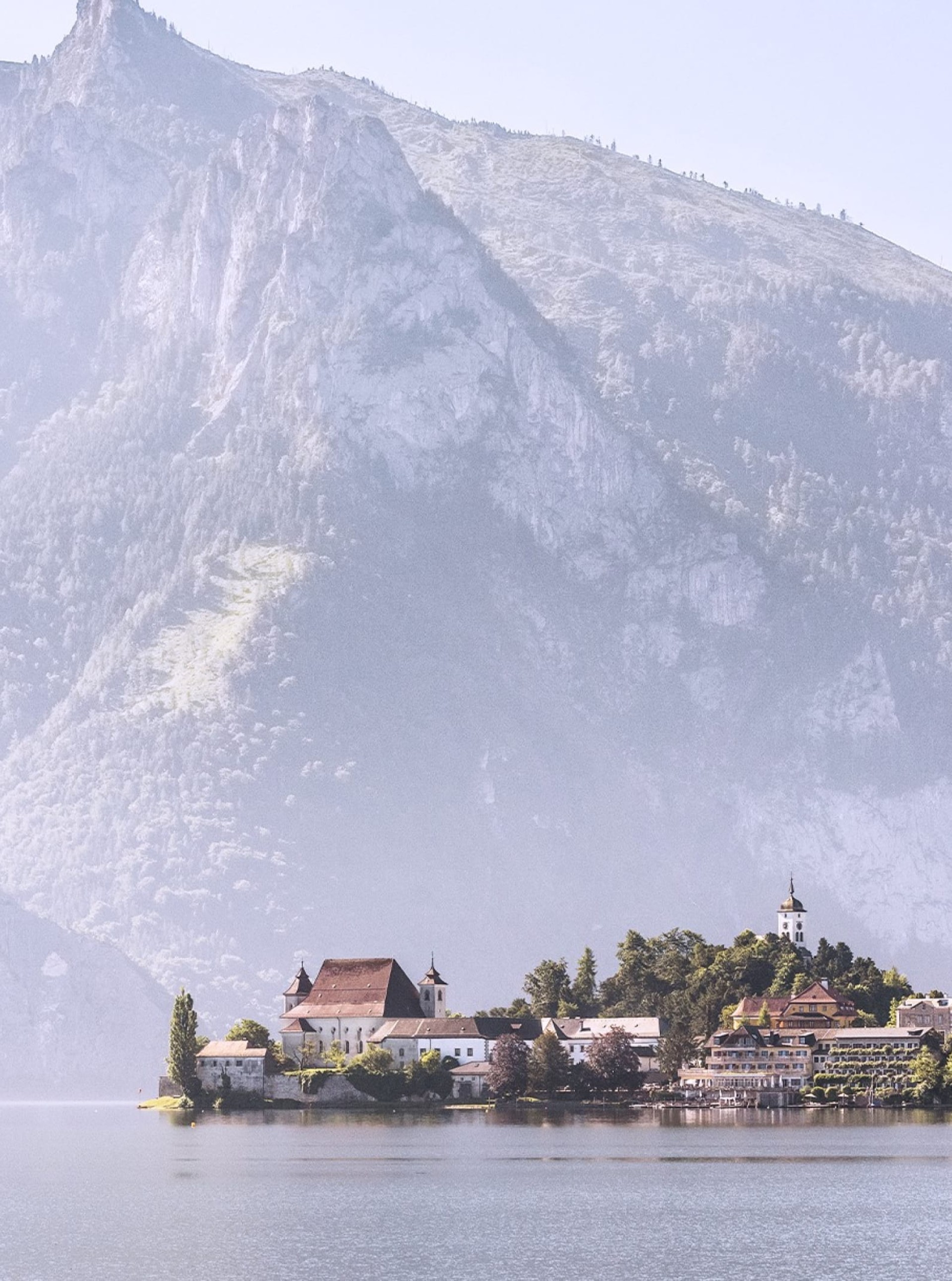 Aussicht auf Schloss Ort und den Traunsee, mit Bergen im Hintergrund.