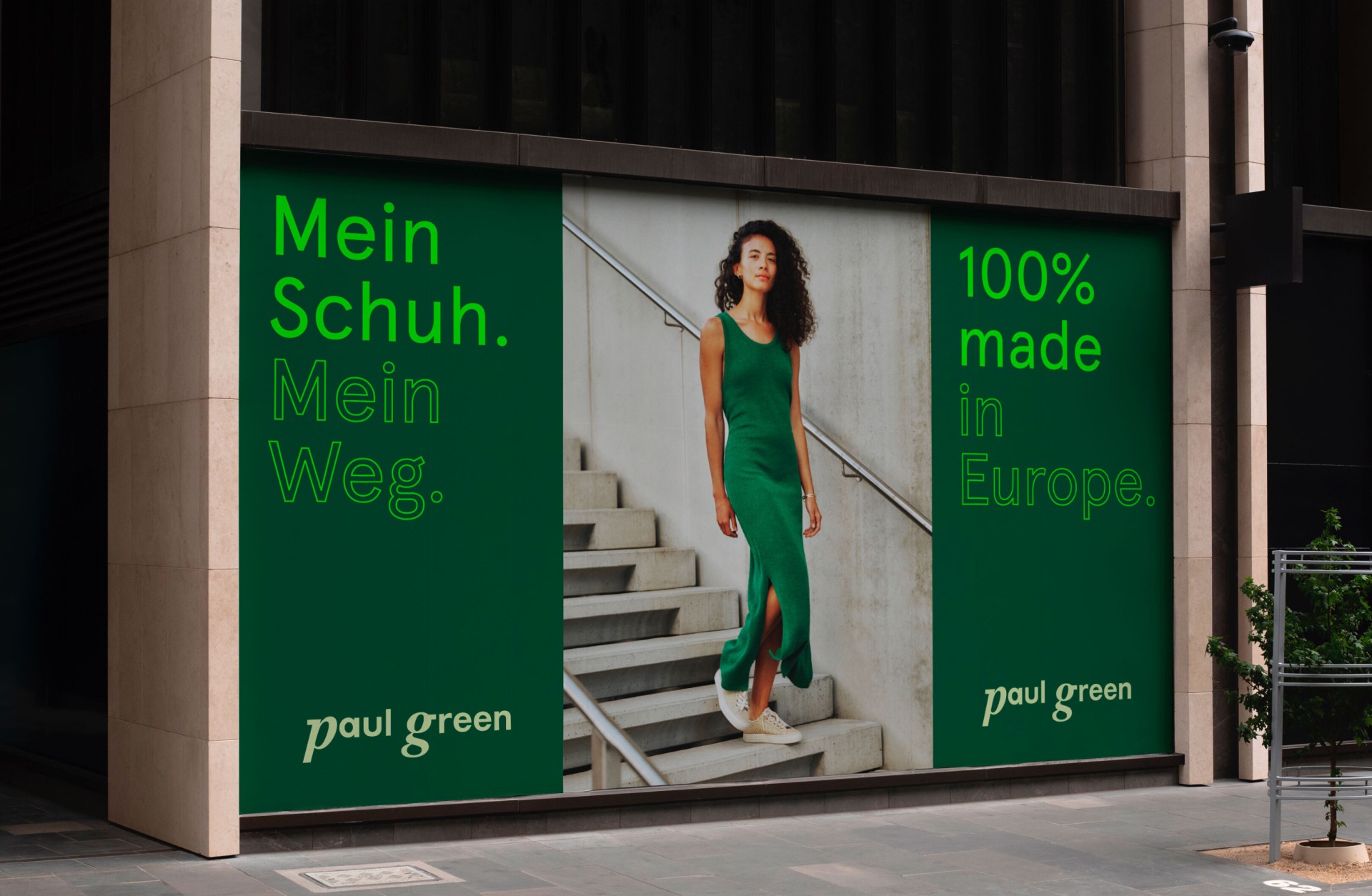 Eine Paul Green-Werbung mit einer Frau in Grün auf einer Treppe. Text: „Mein Schuh. Mein Weg.“ und „100 % Made in Europe“.