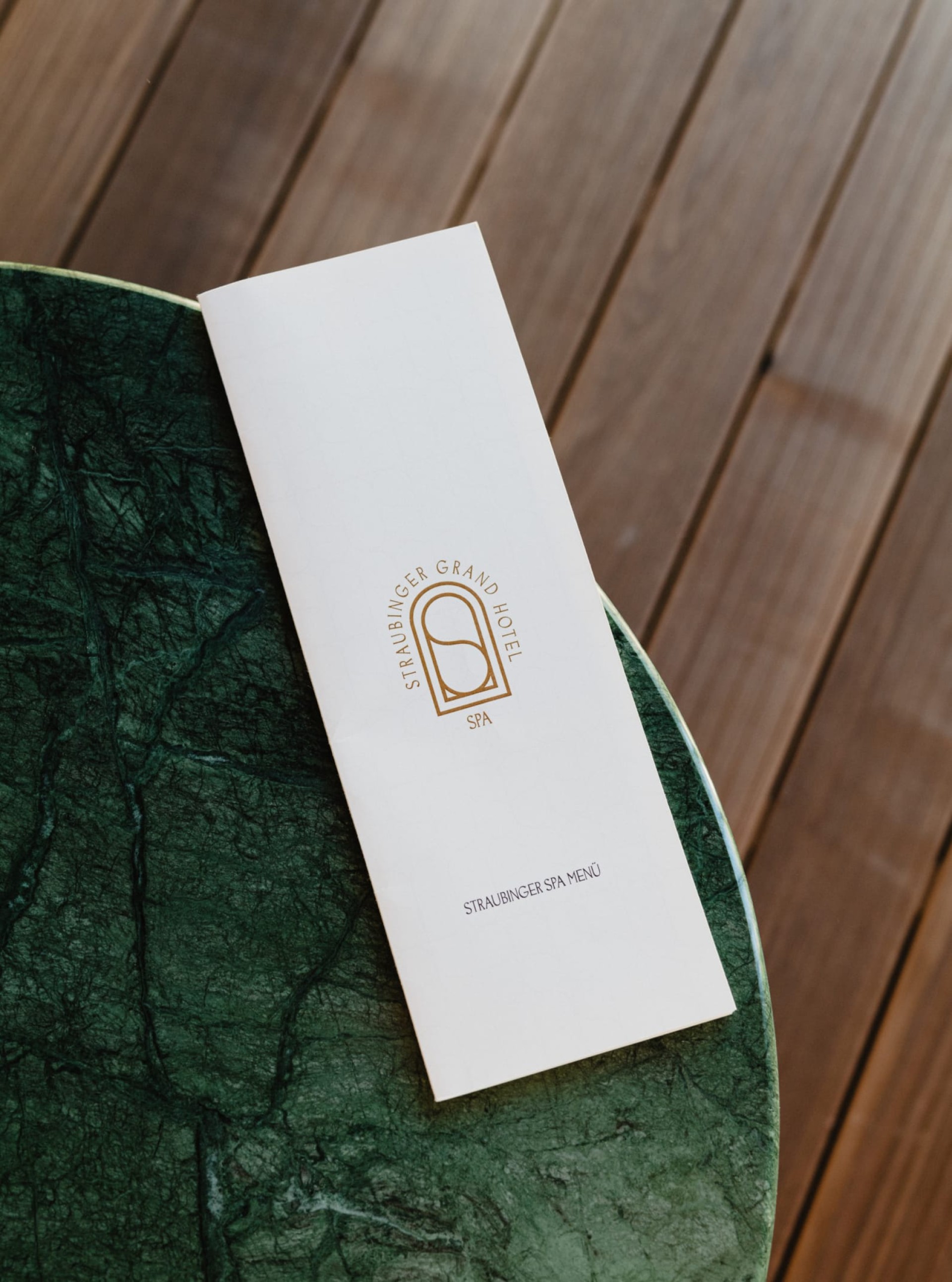 Straubinger Grand Hotel Spa-Menü auf grünem Marmortisch mit Holzboden.
