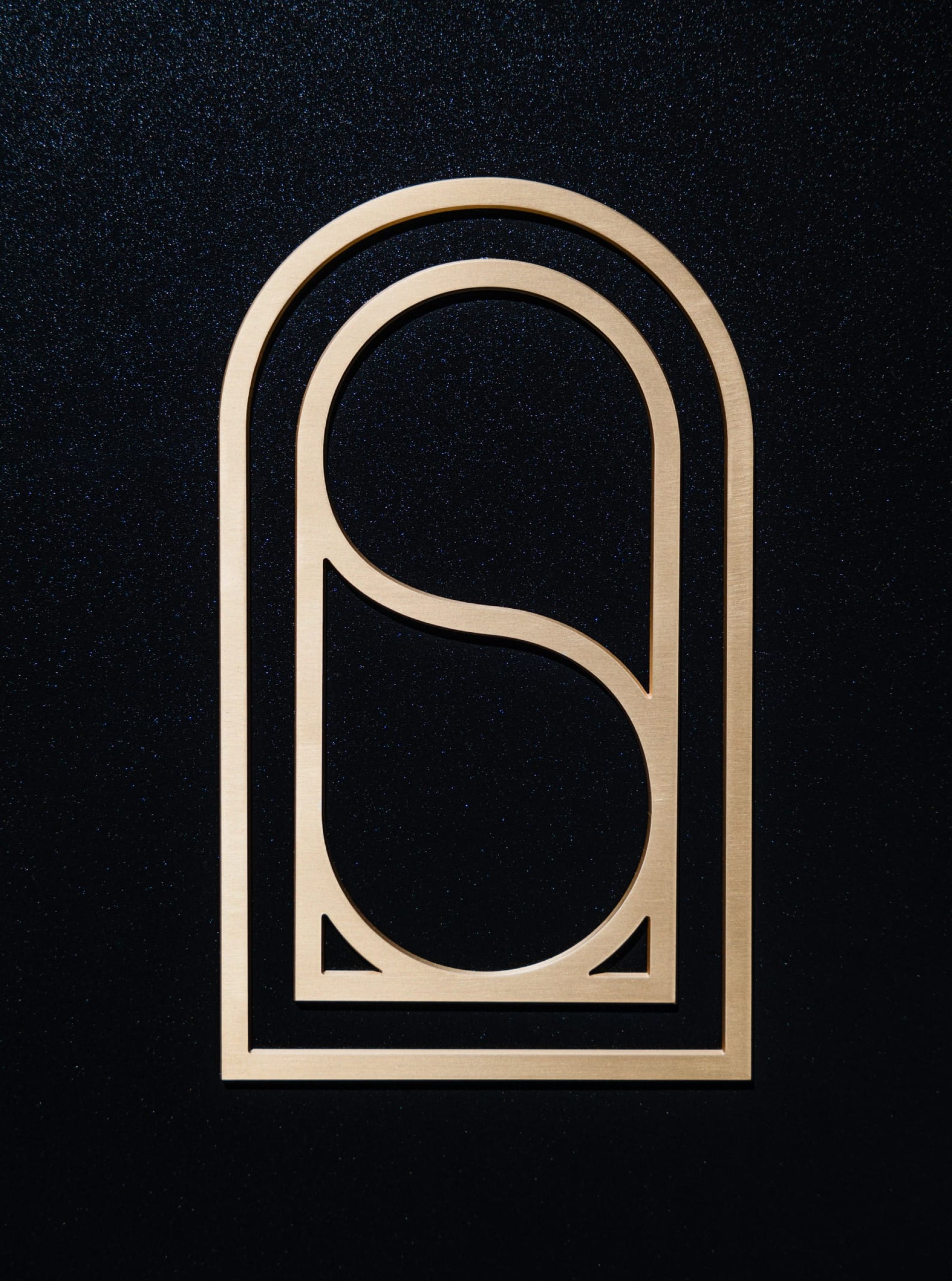 Goldene architektonische S-Form auf strukturiertem schwarzen Hintergrund.