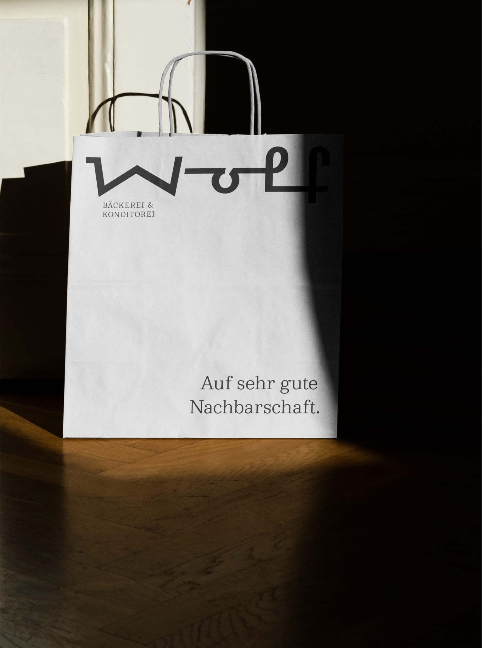 Eine weiße Einkaufstüte "Wolf Bäckerei & Konditorei" mit dem Slogan "Auf sehr gute Nachbarschaft".
