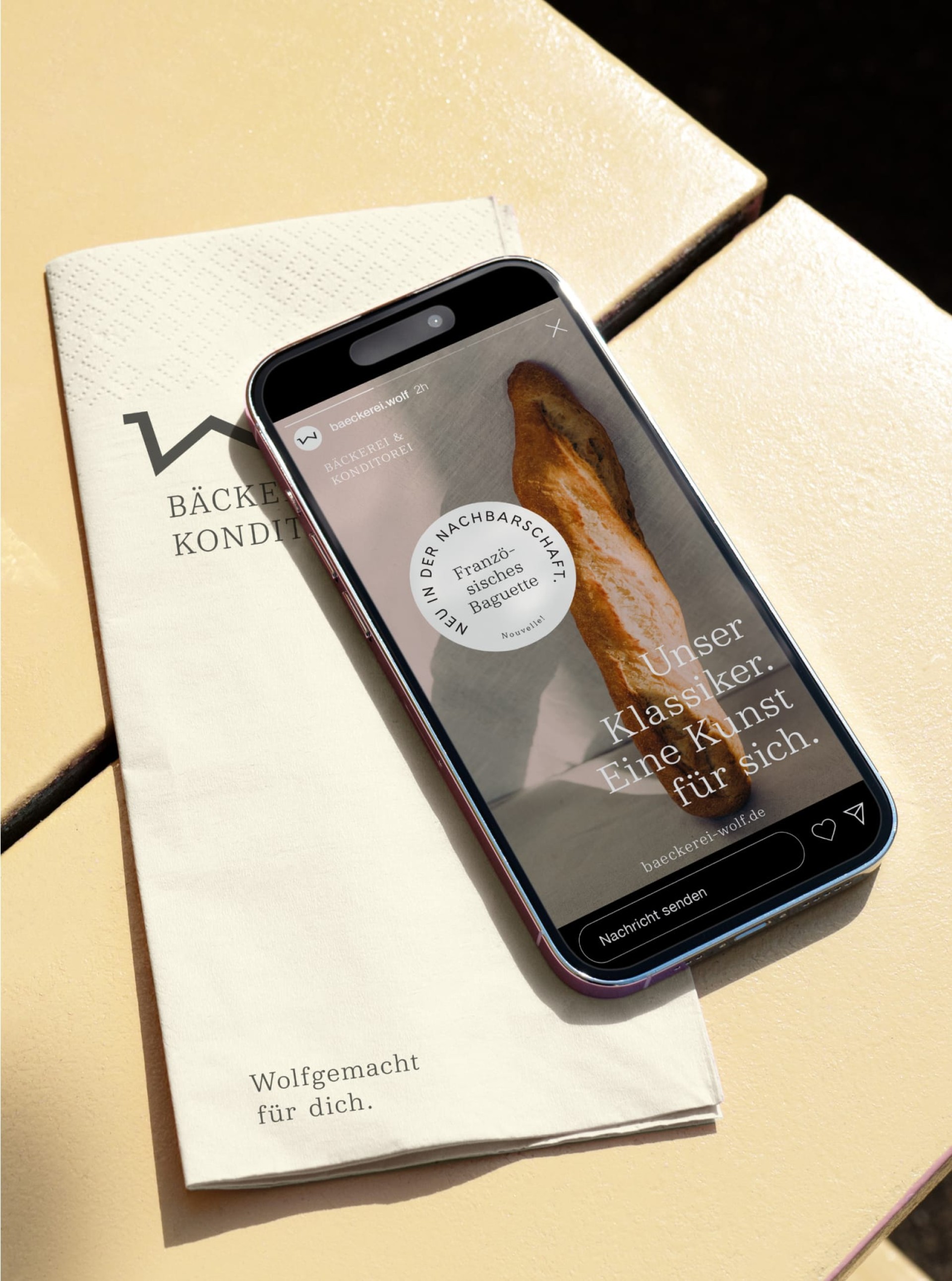 Ein Handy zeigt ein Instagram-Post von baeckerei.wolf mit Baguette. Bäckerei Wolf Broschüre daneben.