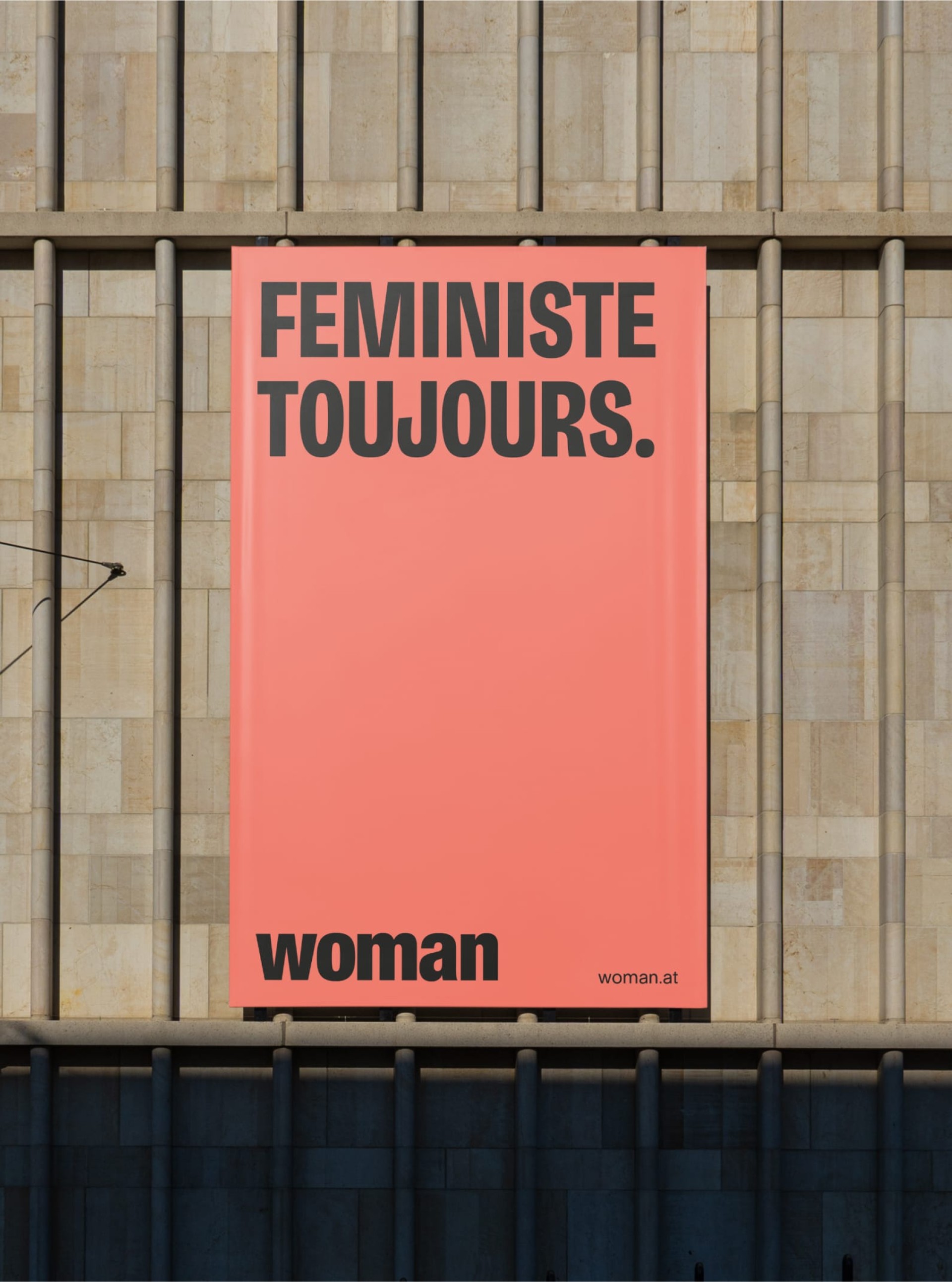 Ein Poster mit dem Text "FEMINISTE TOUJOURS.", "woman" und "woman.at" hängt an einer Wand.