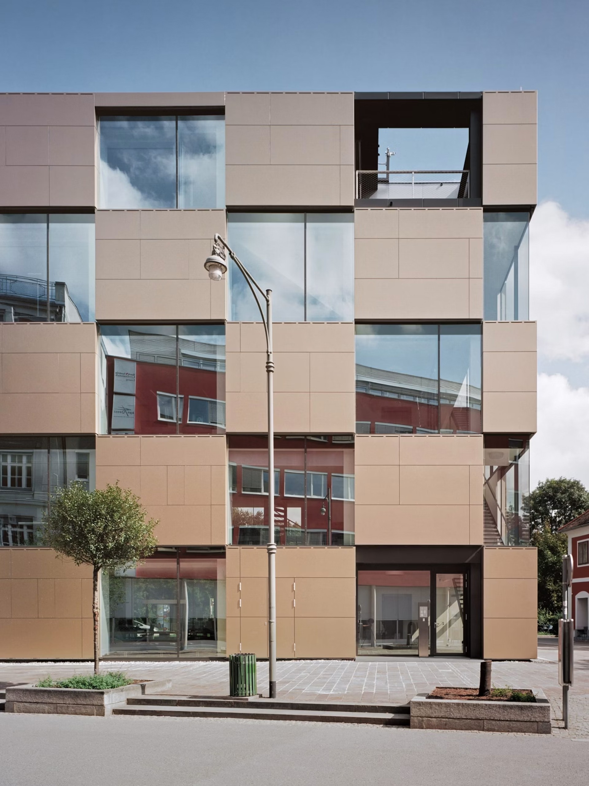 Ein Gebäude mit einer Fassade aus quadratischen Paneelen und Fensterglas unter einem blauen Himmel.