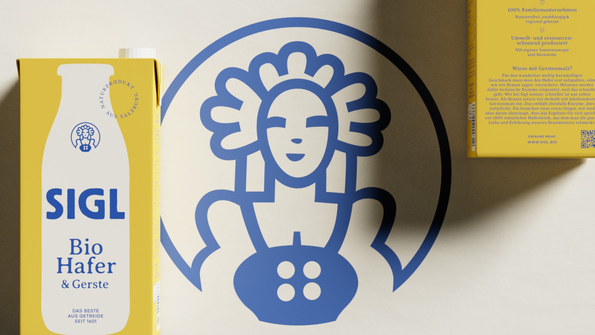 Ein gelber SIGL Bio Hafer & Gerste Karton mit einem blauen Logo einer Frau auf dem Karton und im Hintergrund.