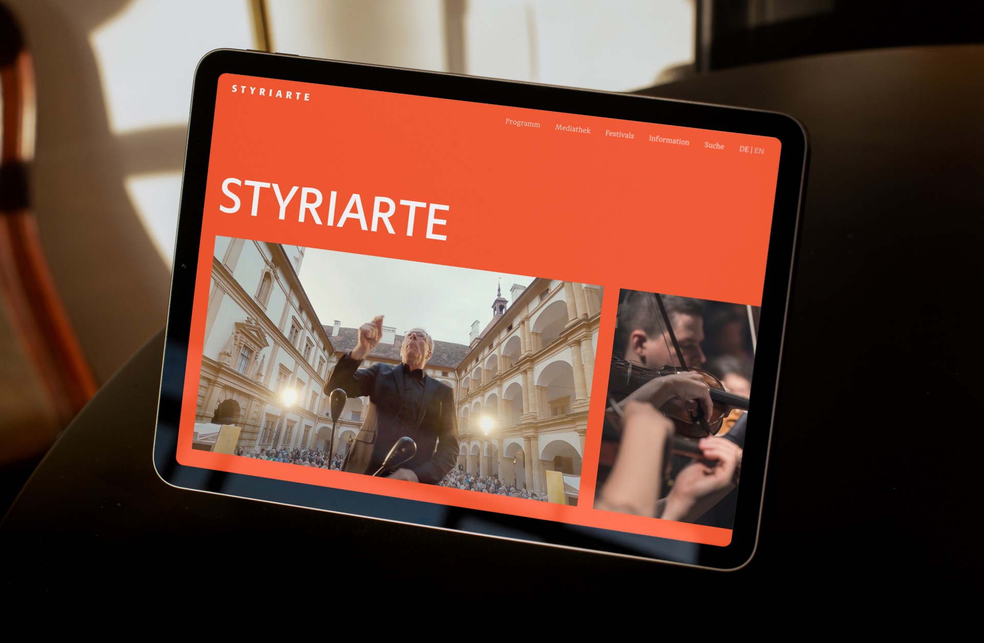 Auf einem Tablet wird die Website der Styriarte mit einem Dirigenten und Musikern angezeigt.