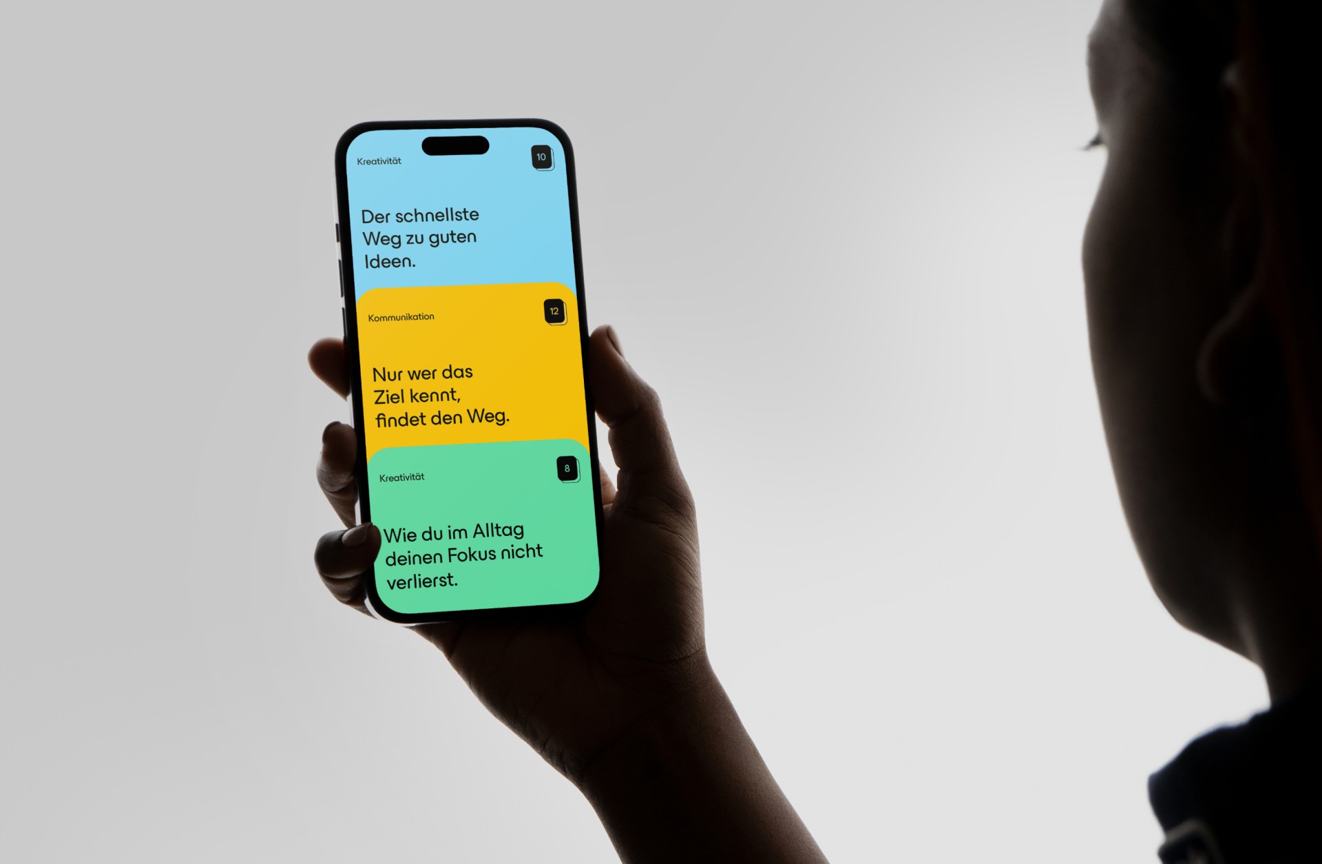 Eine Person hält ein Smartphone mit Text zu Kreativität und Kommunikation.
