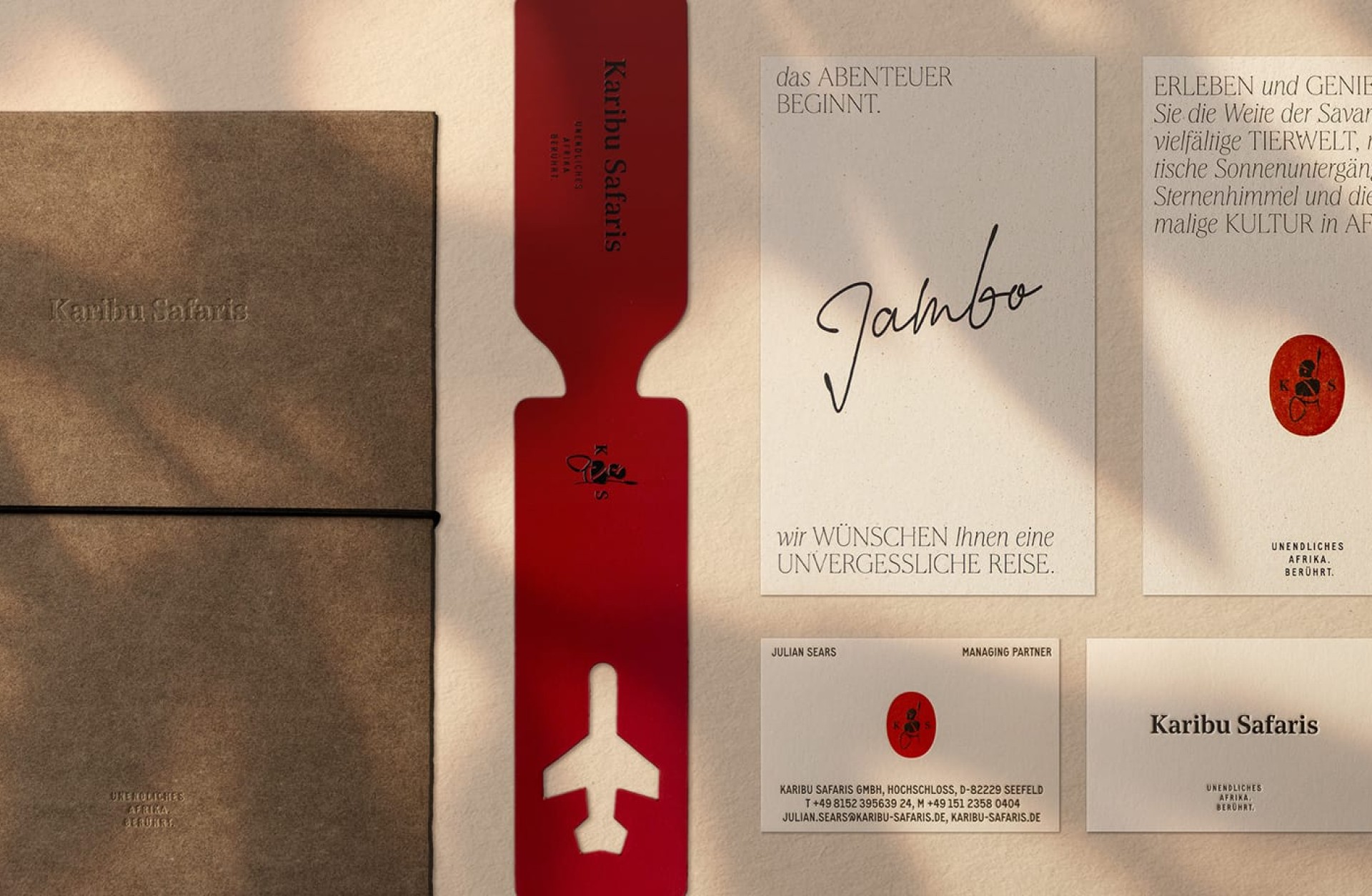 Visuelle Darstellung von Karibu Safaris-Branding-Materialien mit Broschüre, Lesezeichen, Notizen und Visitenkarten.