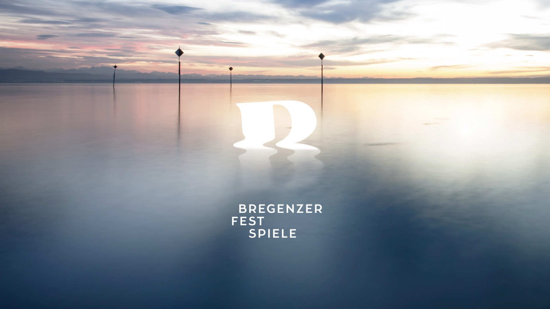Seebühne Bregenz mit dem Logo der Bregenzer Festspiele und dem Bodensee im Hintergrund bei Sonnenaufgang.