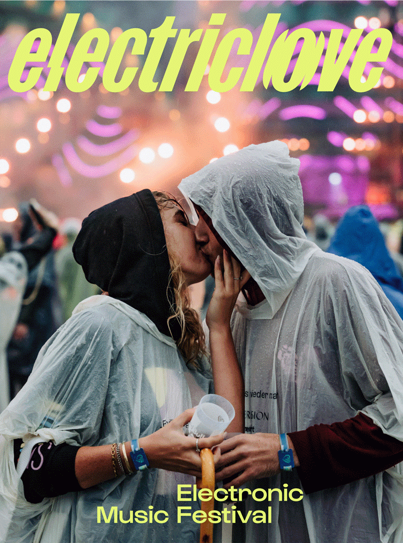 Ein Paar küsst sich beim "Electriclove Music Festival". Beide tragen Regenmäntel und Festivalbändchen.